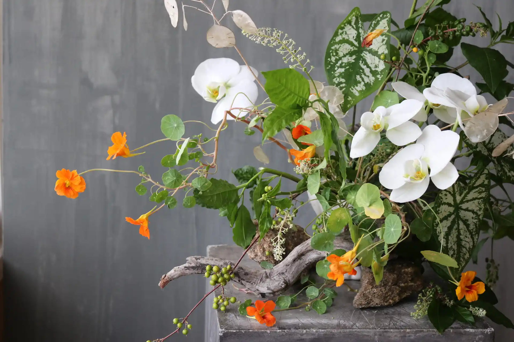 Floral arrangement with white orchids and orange flowers in wild tropic style by Shaa.Project the art studio denver