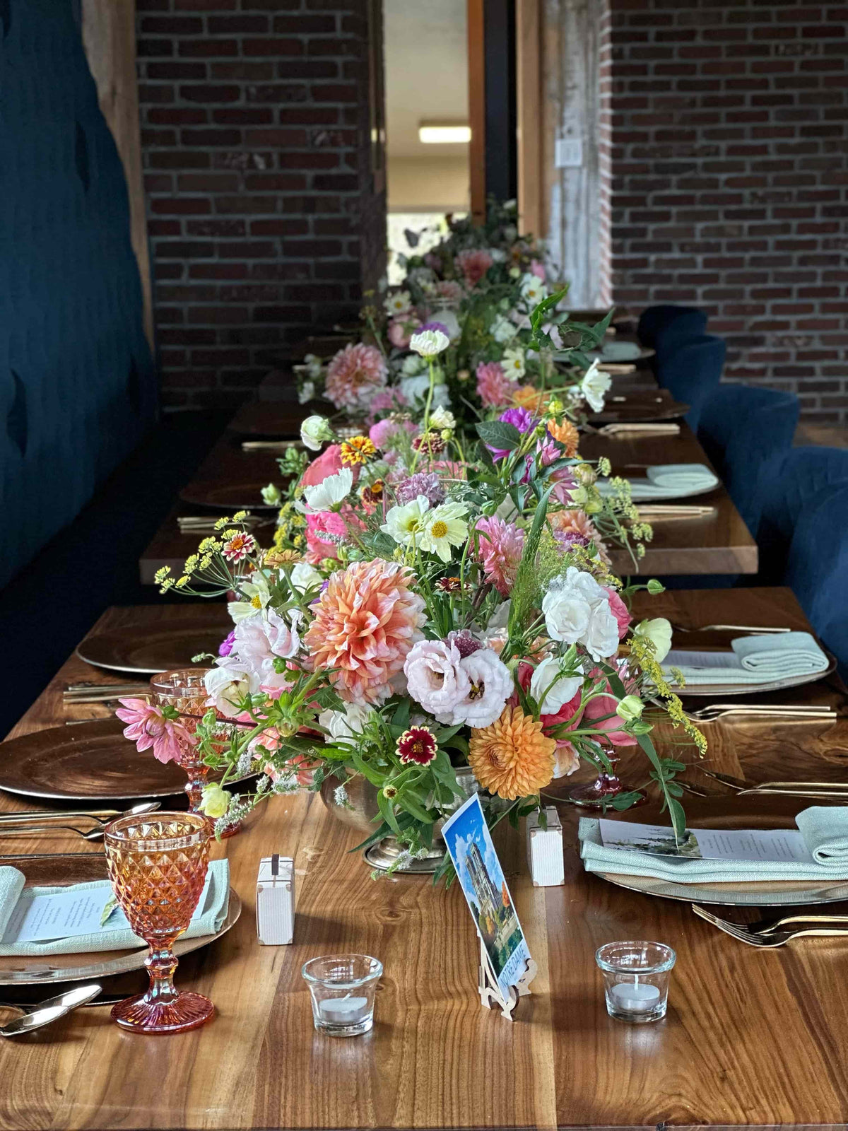 Decorative floral arrangement on a wooden table with cutlery and glasses. Colorado event flower studio