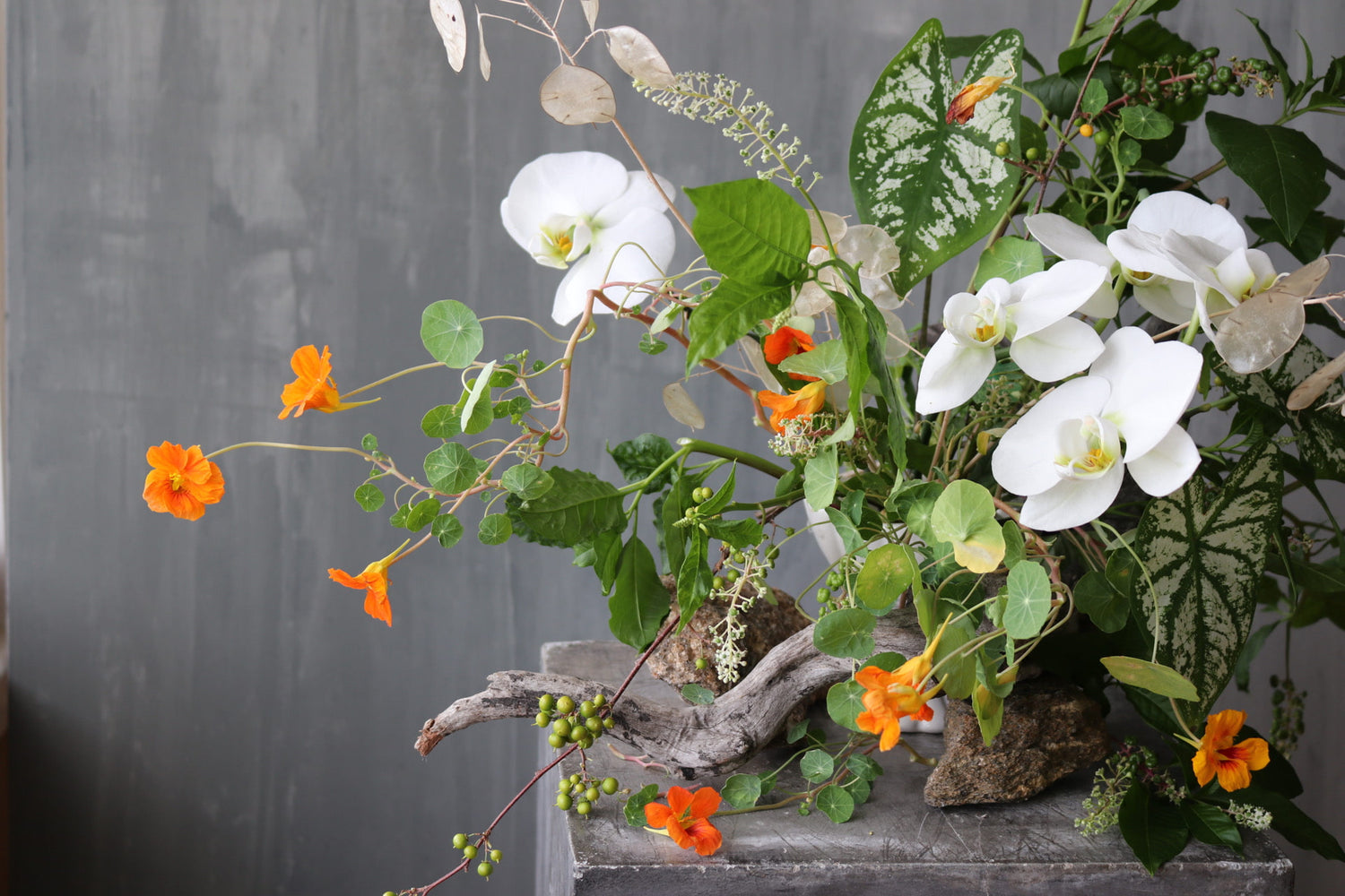 Floral arrangement with white orchids and orange flowers with wild tropical vibes