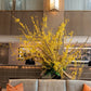Decorative yellow floral arrangement in a modern interior setting with a couch and lamp.
