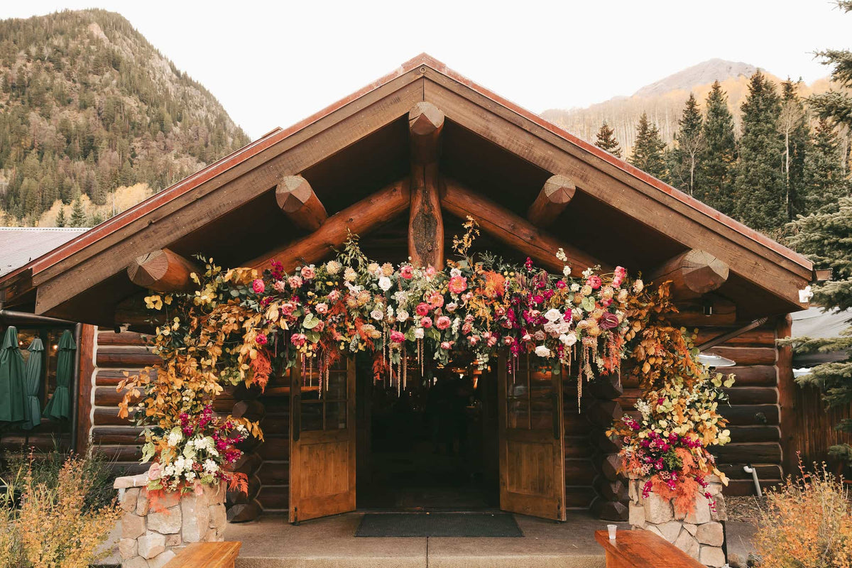 Wooden cabin entrance decorated with colorful flowers in Aspen wedding venue 