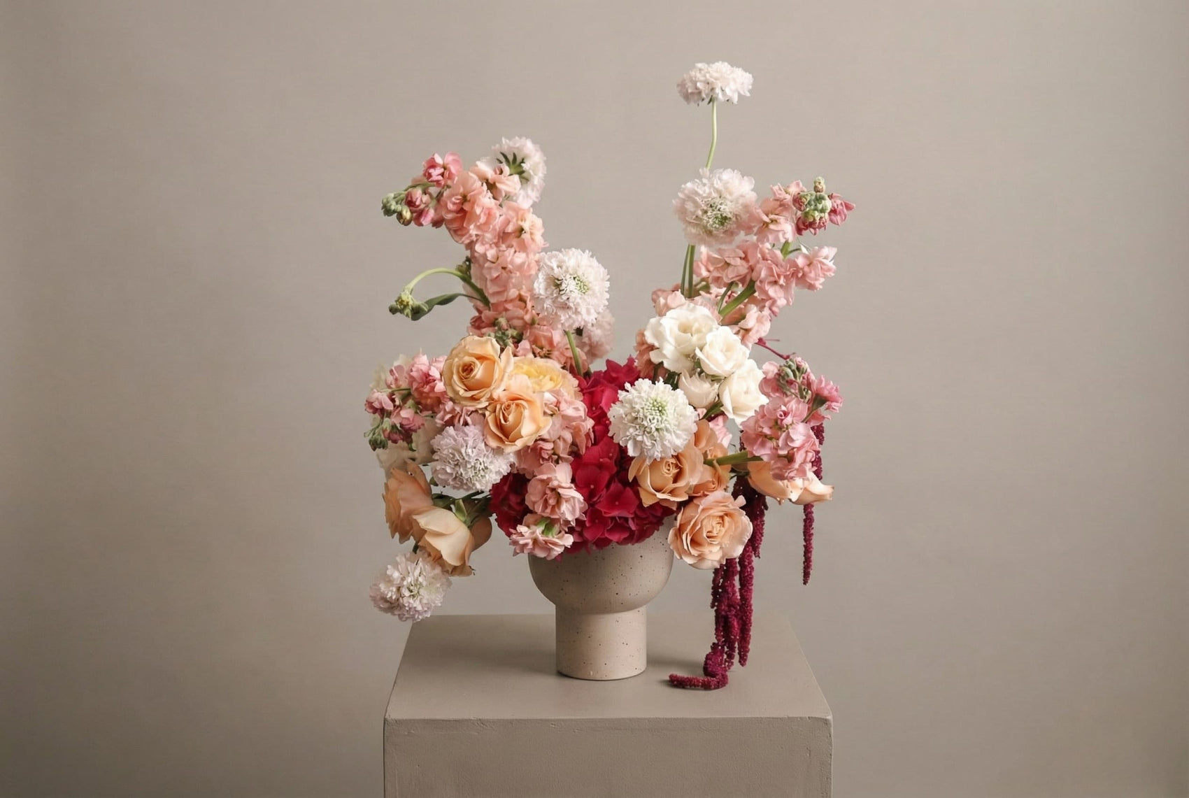 Romantic anniversary flower arrangement with blush roses, pink blooms, and red hydrangea in a modern ceramic vase