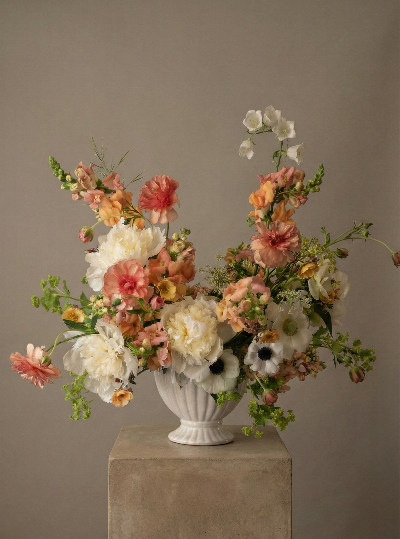 Apricot designer flower arrangement in a white urn vase with peach, coral, and creamy blooms, styled in an airy sculptural design by Shaa.Project in Denver and Boulder.