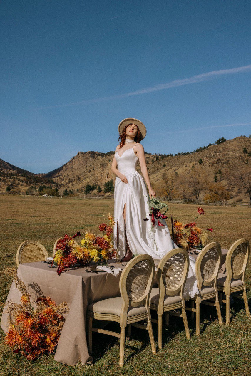 Woman in a white dress standing by a table with floral arrangements Loveland wedding venue 