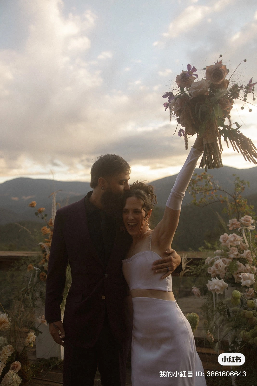 Couple on their wedding day with a scenic background of mountains and flowers.