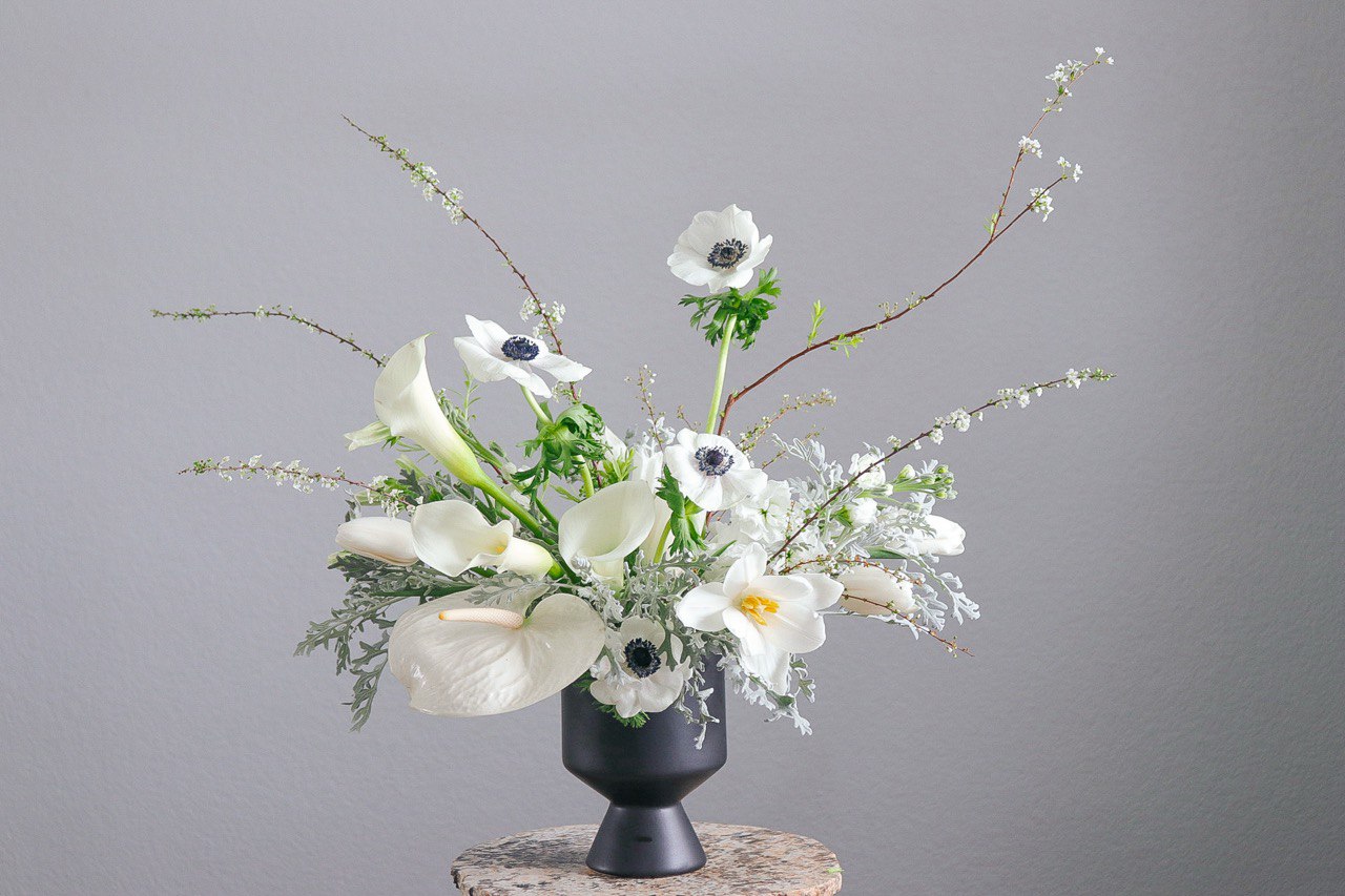 white sympathy flower arrangement with calla lilies, anemones, and delicate branches