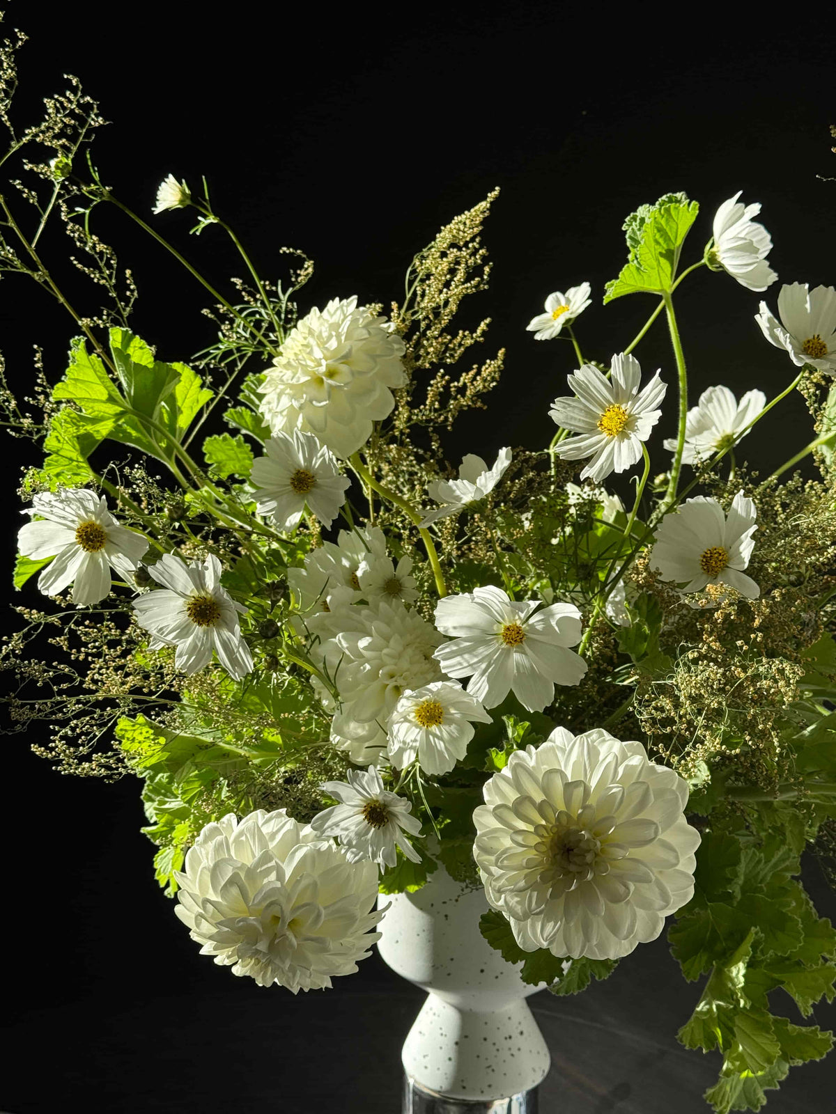 white sympathy flower arrangement with dahlias and cosmos in a ceramic vase