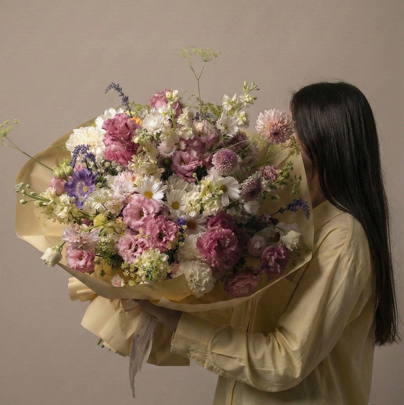 Person holding a large bouquet of flowers against a plain background