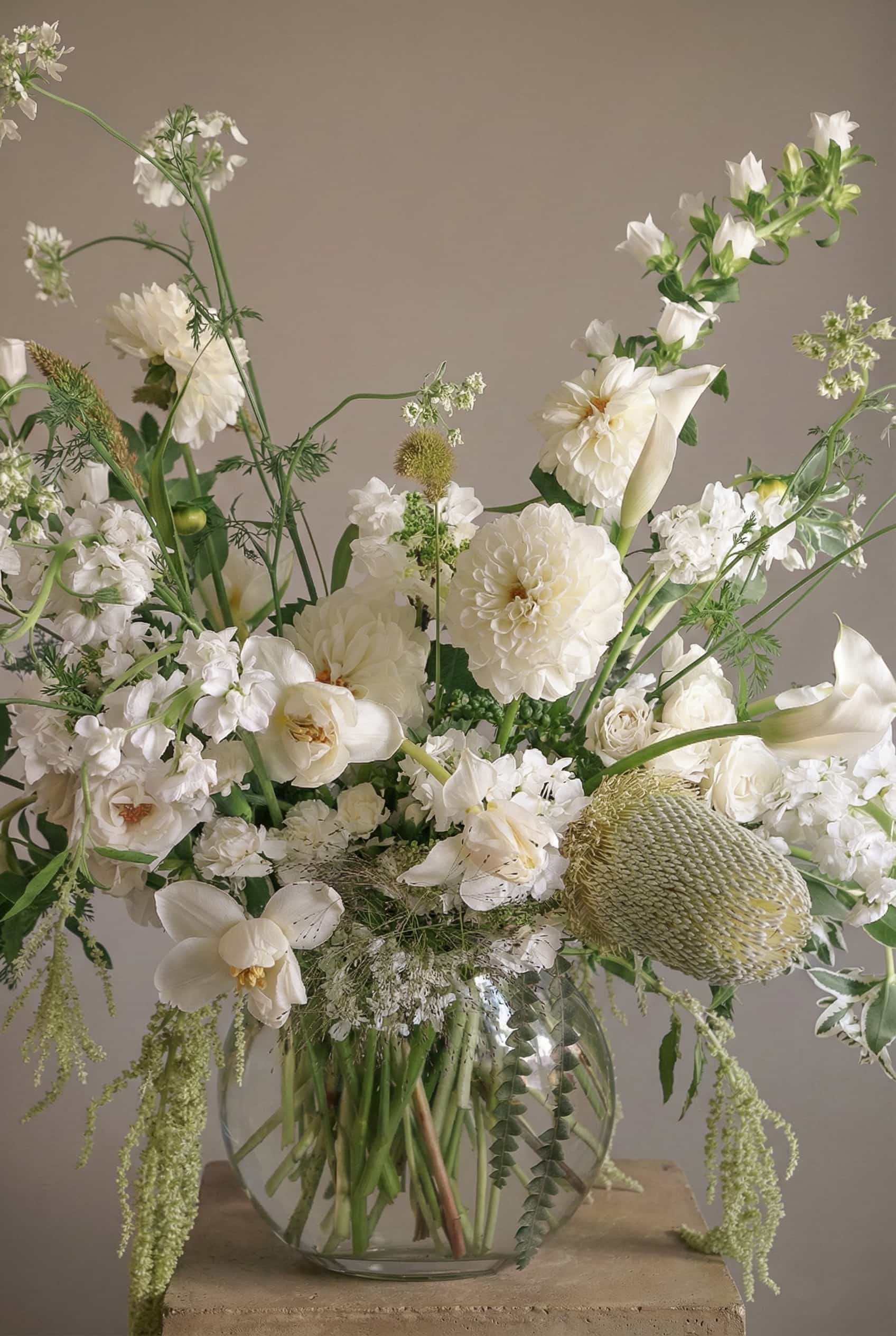 Wishing white flower arrangement with dahlias, orchids, and airy seasonal blooms in a glass vase